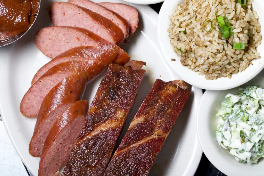 sliced sausage and ribs with a side of dirty rice and coleslaw. Texas Style Barbecue