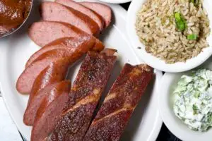 sliced sausage and ribs with a side of dirty rice and coleslaw. Texas Style Barbecue